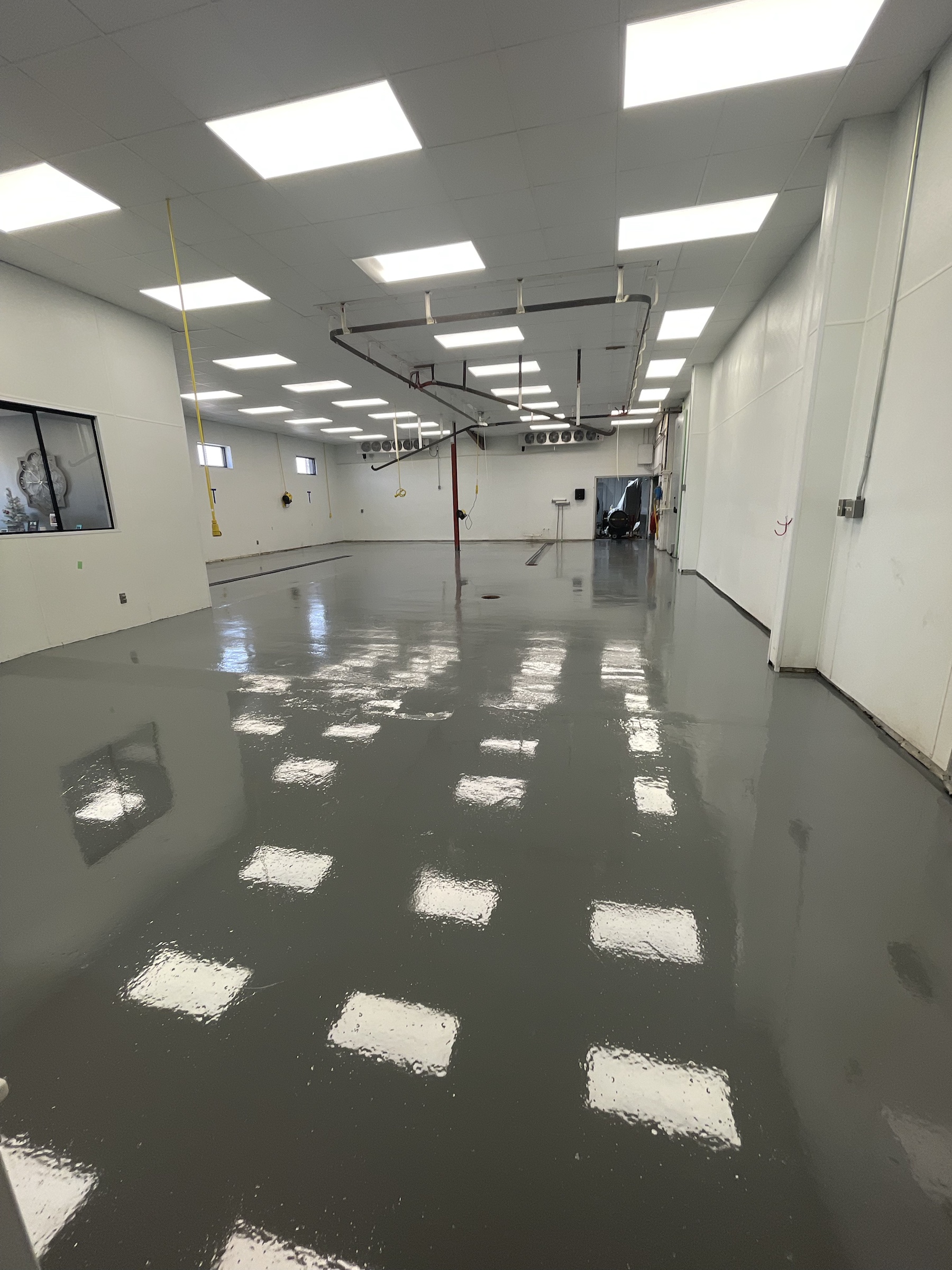 Glossy gray Rezena Classic floor in a bright industrial workspace