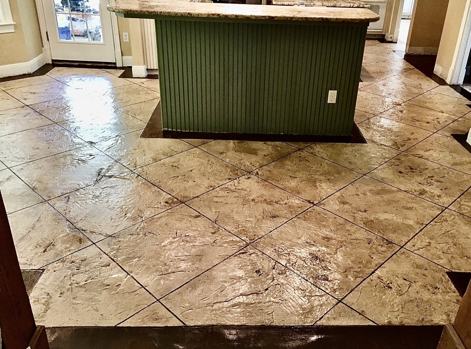 Finished tan PetraStamp floor with diagonal scoring around a kitchen island